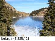 Ice-covered alpine lake Kolsai in winter with fir trees in sunny weather. Стоковое фото, фотограф Natalya Danilova / Фотобанк Лори