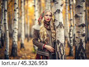 A beautiful girl in a traditional Russian folk shawl in a autumn birch grove. The portrait symbolizes the traditions and beauty of the Russian people. Стоковое AI-изображение, AI-художник Photojuli / Фотобанк Лори
