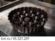 Round baking dish with central cakelet mold and fluted edges standing on metal table. Стоковое AI-изображение, AI-художник Иван Рябоконь / Фотобанк Лори