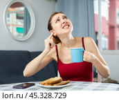 Annoyed woman drinking coffee and covering ear, disturbed by loud neighbours. Стоковое фото, фотограф Яков Филимонов / Фотобанк Лори
