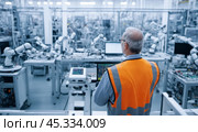 Engineer in safety vest operating robotic arms, manufacturing setting, modern automation technology, human oversight, control panel operation, advanced factory floor, precision production. Стоковое AI-изображение, AI-художник Павел Муравьев / Фотобанк Лори