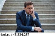 Upset and worried businessman sitting on stairs after being laid off from job or bankruptcy. looks stressed having problems at work, business failure, project loss. Стоковое AI-изображение, AI-художник Павел Муравьев / Фотобанк Лори