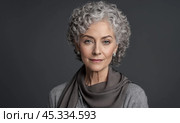 Elegant senior woman with gray hair in stylish scarf posing against dark background, portrait of aging gracefully with confident gaze into camera. Стоковое AI-изображение, AI-художник Павел Муравьев / Фотобанк Лори