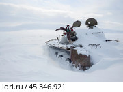 Сломанный старый советский танк на заброшенном полигоне в Арктике. Брошенная военная техника среди заснеженной тундры. Искусственные цветы в стволе взорванной танковой пушки. Память о холодной войне. Чукотка, Дальний Восток России. Стоковое фото, фотограф Андрей Степанов / Фотобанк Лори