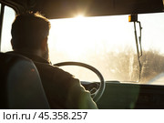 Driver turns steering wheel of truck, bus at sunset time. Skilled chauffeur drives lorry to deliver freight. Cargo shipping service. Drives Journey. Drivers silhouette against a vivid sundown. Travel. Стоковое AI-изображение, AI-художник Марина Демидюк / Фотобанк Лори