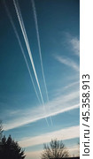 Chemtrail conspiracy theory. Long-lasting condensation trails left in sky by high-flying aircraft are actually chemtrails consisting of chemical or biological agents, sprayed for nefarious purposes. Стоковое AI-изображение, AI-художник Юлия Петровская / Фотобанк Лори