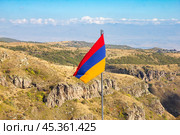 Aerial drone view to flag of Armenia and famous Vahramashen Church of the 11th century, near Amberd fortress in sunny summer day. Cliff with Arkashian River deep in canyon. Aragatsotn region, Armenia. Стоковое фото, фотограф Алексей Ширманов / Фотобанк Лори