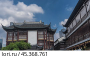 Ancient traditional Chinese architecture. Buildings with curved roofs, carved ornaments, and patterns on the facade. Blue sky, clouds. Modern skyscrapers are visible in the distance. Shanghai. Стоковое фото, фотограф Вера Ивановна Кубарева / Фотобанк Лори
