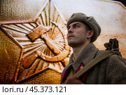 Мужчина в военной форме времен Великой Отечественной войны идет по Красной площади в центре города Москвы на фоне символа советкой красной армии, Россия. Редакционное фото, фотограф Николай Винокуров / Фотобанк Лори
