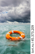 Orange lifebuoy floating on ocean waves under storm clouds symbolizing hope and rescue. Стоковое AI-изображение, AI-художник Юрий Поздников / Фотобанк Лори