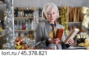 Elderly lady selects suitable product from nougat assortment. Стоковое видео, видеограф Яков Филимонов / Фотобанк Лори
