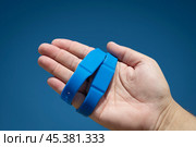 Синий водонепроницаемый бесконтактный RFID браслет на руке на фоне синего неба. Стоковое фото, фотограф Дорощенко Элла / Фотобанк Лори