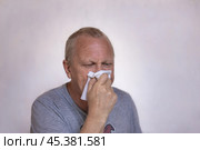 An elderly man sneezes and coughs into a paper napkin. Diseases of viral infections. Стоковое фото, фотограф Коханова Наталья / Фотобанк Лори