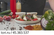 Salad, garnished with scattering of sesame seeds, is laid out on kitchen table amidst array of vegetables and salad components. Стоковое видео, видеограф Strunov David / Фотобанк Лори