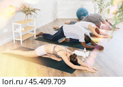 Women and men doing Eka Pada Rajakapotasana during group yoga training. Стоковое фото, фотограф Яков Филимонов / Фотобанк Лори