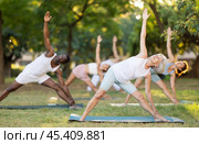 Elderly woman practices yoga pose Anjaneyasana with other people of different nationalities in summer park. Стоковое фото, фотограф Яков Филимонов / Фотобанк Лори