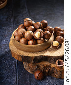 Freshly cracked macadamia nuts in a rustic bowl on a wooden surface, highlighting their natural texture and rich color. Стоковое фото, фотограф Евгения Трушкова / Фотобанк Лори