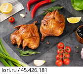 Deliciously roasted whole chickens served on a wooden board surrounded by fresh vegetables and herbs in a bright kitchen setting. Стоковое фото, фотограф Евгения Трушкова / Фотобанк Лори