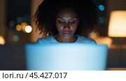 Сосредоточенная афроамериканская деловая женщина, работающая за ноутбуком в тускло освещенном офисе поздно вечером. Стоковое AI-изображение, AI-художник ФотоИнтеллект / Фотобанк Лори