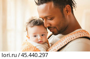 Father holding his baby in a baby sling, showing love and care. Стоковое AI-изображение, AI-художник Юрий Поздников / Фотобанк Лори