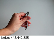 Маникюрные щипчики в женской руке на белом фоне. Стоковое фото, фотограф Hanna Shapialevich / Фотобанк Лори