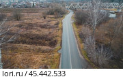 The camera floats over a deserted area in late autumn. All nature and people froze in anticipation of winter and cold weather. A railway bridge over the river is visible in the distance. Aerial photography from a drone. Стоковое видео, видеограф Ярославский Максим / Фотобанк Лори