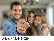Homeowners. Happy young Caucasian family spouses standing indoors holding car house flat apartment keys, celebrating new purchase buying real estate. Mortgage loan. New home. Mother, father and child. Стоковое AI-изображение, AI-художник Марина Демидюк / Фотобанк Лори