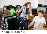 Strict teacher reprimanding negligent teenage student in computer class. Стоковое фото, фотограф Яков Филимонов / Фотобанк Лори