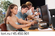 Concentrated young girl studying in computer lab with fellow students engrossed in coursework. Стоковое видео, видеограф Яков Филимонов / Фотобанк Лори
