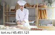 Young woman works in bakery as baker, kneads dough, works with flour. Стоковое видео, видеограф Яков Филимонов / Фотобанк Лори