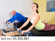 Smiling woman performing pilates on reformer in fitness studio. Стоковое фото, фотограф Яков Филимонов / Фотобанк Лори