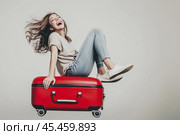 Young woman is riding on her travel suitcase. Стоковое AI-изображение, AI-художник Дмитрий Киселёв / Фотобанк Лори