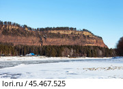 View of the Shamansky cliff on the bank of the Irkut River in November during the ice cover of the river. The cliff is a natural landmark of the Irkutsk region and a tourist destination. Scenic landscape. Стоковое фото, фотограф Виктория Катьянова / Фотобанк Лори
