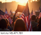 Evening Background of crowd at political rally in the United States carrying US flags. Upcoming election cycle 2024 presidential campaigns, protests against unfair elections, shallow depth of field, Стоковое AI-изображение, AI-художник Sergey Grishin / Фотобанк Лори