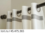 Curtain rod. Curtain on a metal rod with grommets close up. Bracket for curtain rod eaves and pole against white backdrop. Soft flowing fabric. Simple elegant design. Metal clip guide for window tulle. Стоковое AI-изображение, AI-художник Марина Демидюк / Фотобанк Лори