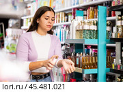 Satisfied young woman chooses and tries perfume in cosmetics store. Стоковое фото, фотограф Яков Филимонов / Фотобанк Лори