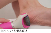Close-up of electric foot file being used to remove calluses from a heel. Skincare and personal grooming concept. A woman of 40 years old. Стоковое видео, видеограф Андрей Журавлев / Фотобанк Лори
