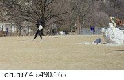 A woman plays with a dog in a clearing, throwing a ball to the dog on a warm winter day. Стоковое видео, видеограф Vladislav Baranov / Фотобанк Лори
