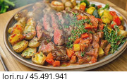 Sizzling grilled steak releasing flavorful steam on a rotating plate of potatoes. Стоковое AI-видео, аниматор Юрий Поздников / Фотобанк Лори
