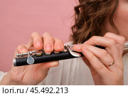 Hands holding a piccolo flute against a pink background. Close-up photography for music and instrumental design concepts. Стоковое фото, фотограф Андрей Журавлев / Фотобанк Лори