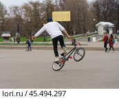 BMX in the Moscow park. Young man doing trick on the bike in the spring day. Extreme sports is very popular among youth. 2019. Стоковое фото, фотограф YuryKara / Фотобанк Лори