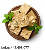Delicious creamy fudge squares with crumble topping and mint leaves on wooden plate. Стоковое AI-изображение, AI-художник Иван Рябоконь / Фотобанк Лори