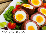 Scotch eggs served with greens and leek, Scottish traditional dish at plate. Стоковое фото, фотограф Яков Филимонов / Фотобанк Лори