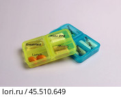 Two pillboxes filled with vitamins, with a reception schedule on a light lilac background. Стоковое фото, фотограф Veronika Belosokhova / Фотобанк Лори