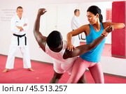 Woman and african american man practice painful grips in self-defense lessons. Стоковое фото, фотограф Яков Филимонов / Фотобанк Лори