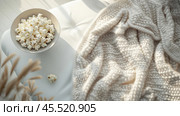 Cozy scene with popcorn and warm blanket for singles awareness day comfort. Стоковое AI-изображение, AI-художник Sabyna75 / Фотобанк Лори