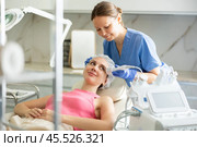 Female cosmetologist performing anti-aging face phototherapy procedure, shrink pores and repair damaged skin for young girl client in clinic of aesthetic medicine. Стоковое фото, фотограф Яков Филимонов / Фотобанк Лори