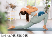 Experienced girl, fitness club teacher, performs crescent moon asana, anjaneyasana. Стоковое фото, фотограф Яков Филимонов / Фотобанк Лори