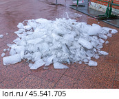 Snow and ice removal from city streets in winter. The ice cleared from the sidewalk is piled up. Removal of snow and ice from the streets of the city in winter. Стоковое фото, фотограф Эдуард Белкин / Фотобанк Лори