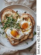 Вид сверху на вкусный завтрак: яйца пашот на тосте с овощами и семенами на бежевой тарелке. Стоковое AI-изображение, AI-художник ФотоИнтеллект / Фотобанк Лори
